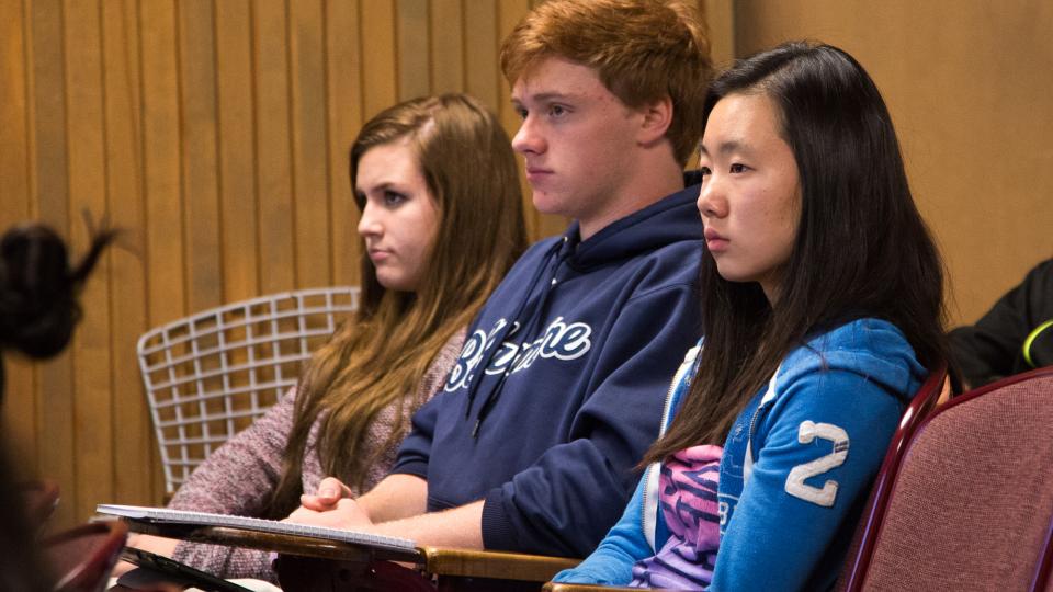 Three students listen to a lecture.